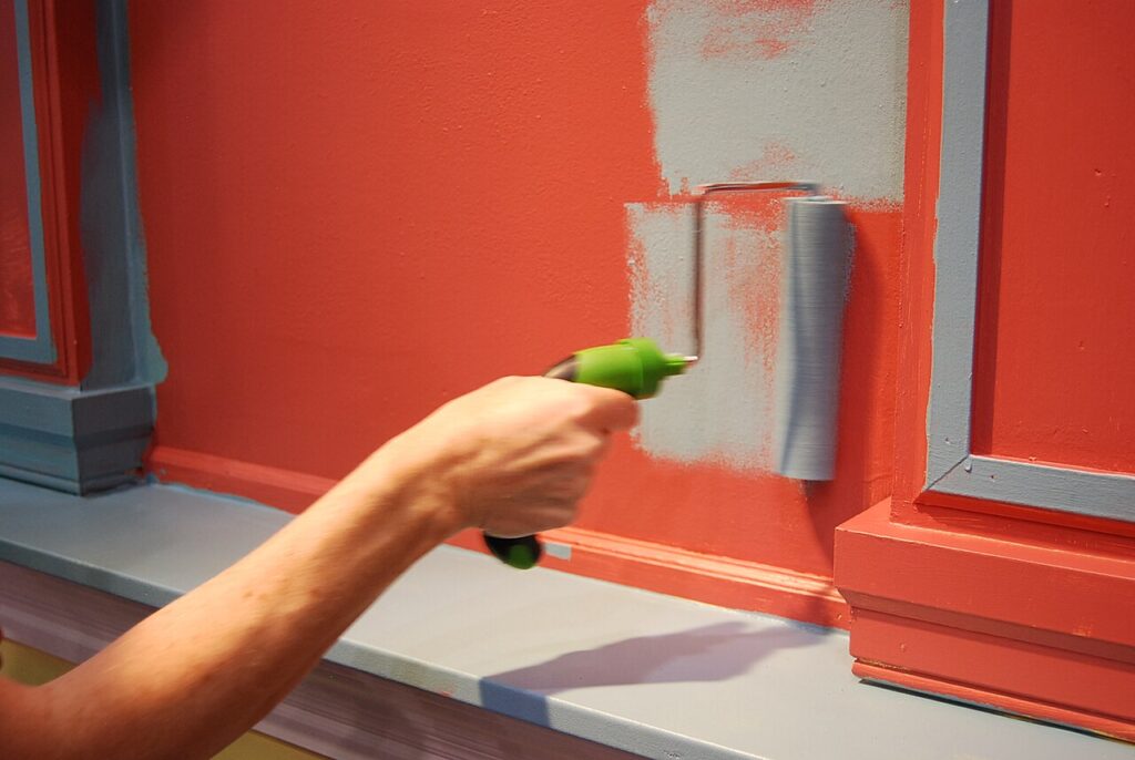 Hand met verfroller schildert een rood houten oppervlak
